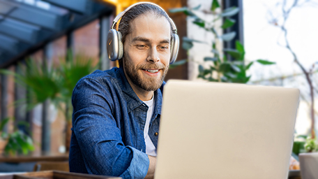 Man sitting with headphones on laptop watching training video