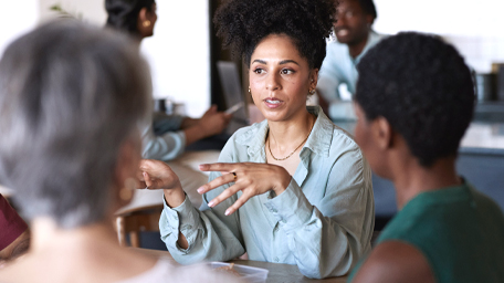 Confident businesswoman discussing with female coworkers while sitting in office cafeteria during break