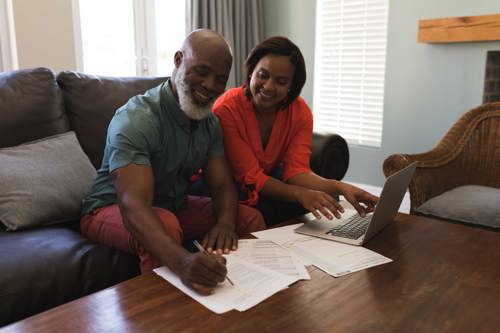 A couple using a laptop and sigining paperwork